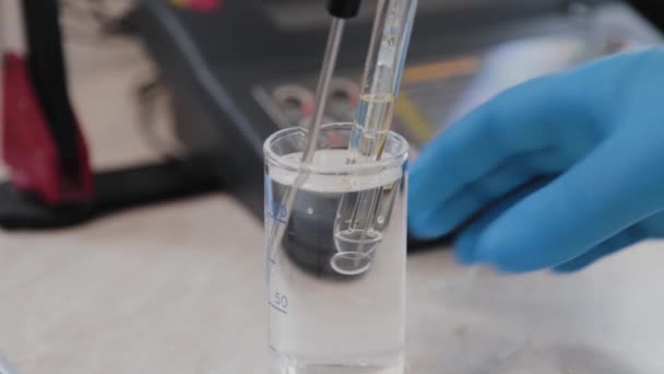 Vrouwelijke wetenschapper controleert vloeistof met een apparaat. — Stockvideo