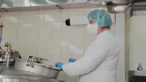 Kobieta naukowiec wkłada składniki do reaktora w celu przygotowania leków. — Wideo stockowe