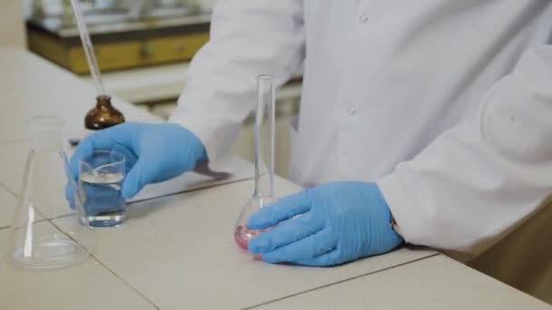 Científico masculino con tubos de ensayo en un laboratorio realiza un experimento . — Vídeo de stock