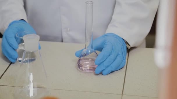 Científico masculino con tubos de ensayo en un laboratorio realiza un experimento . — Vídeos de Stock