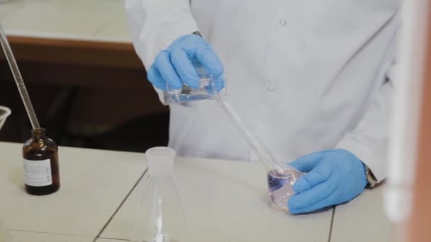 Científico masculino con tubos de ensayo en un laboratorio realiza un experimento . — Vídeo de stock