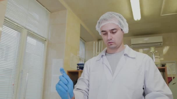 Un scientifique masculin avec éprouvettes dans un laboratoire effectue une expérience . — Video