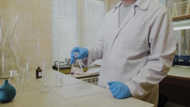 Man wetenschapper met reageerbuizen in een laboratorium voert een experiment uit. — Stockvideo
