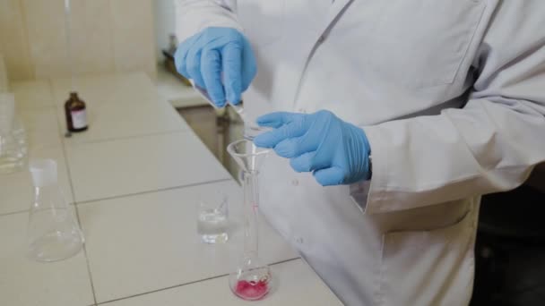 Científico masculino con tubos de ensayo en un laboratorio realiza un experimento . — Vídeos de Stock