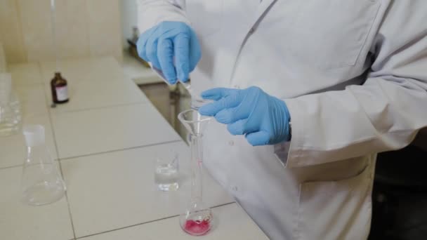 Científico masculino con tubos de ensayo en un laboratorio realiza un experimento . — Vídeo de stock