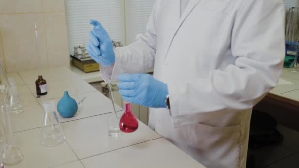 Cientista do sexo masculino com tubos de ensaio em laboratório realiza um experimento . — Vídeo de Stock