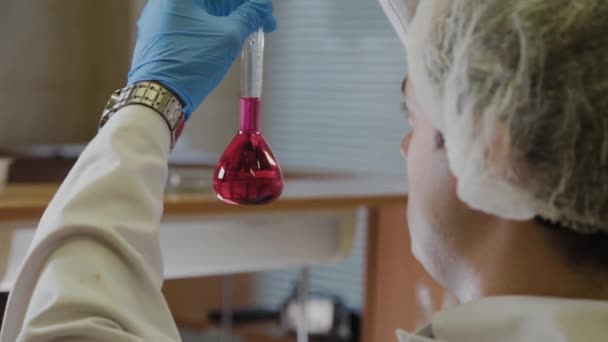 Mężczyzna naukowiec z probówkami w laboratorium przeprowadza eksperyment. — Wideo stockowe