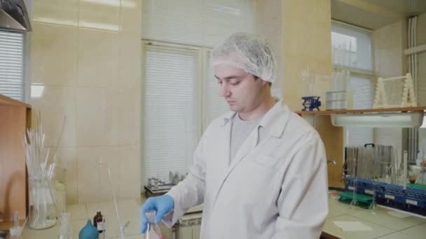 Άνδρας επιστήμονας με δοκιμαστικούς σωλήνες σε ένα εργαστήριο διεξάγει ένα πείραμα. — Αρχείο Βίντεο