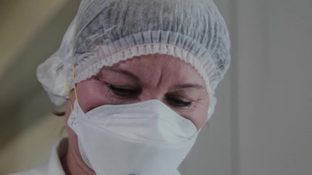 Oudere wetenschapper vrouw met een wit masker. — Stockvideo
