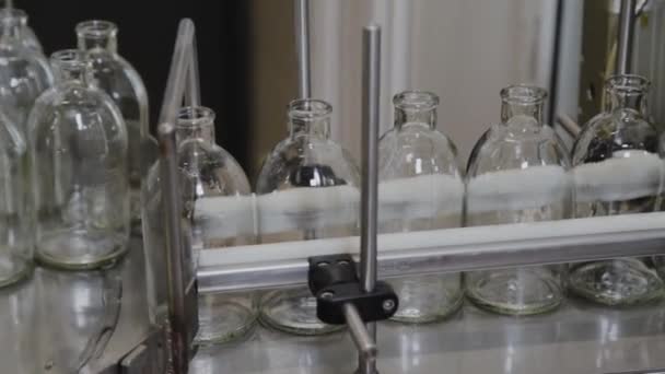 Glass sterile medicine bottles on a conveyor belt for filling with contents. — Stock Video