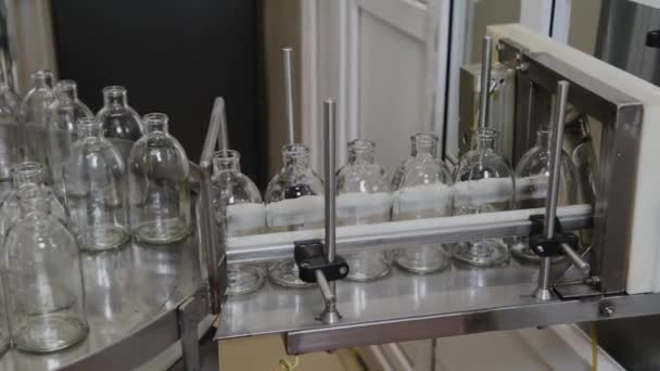 Glass sterile medicine bottles on a conveyor belt for filling with contents. — Stock Video