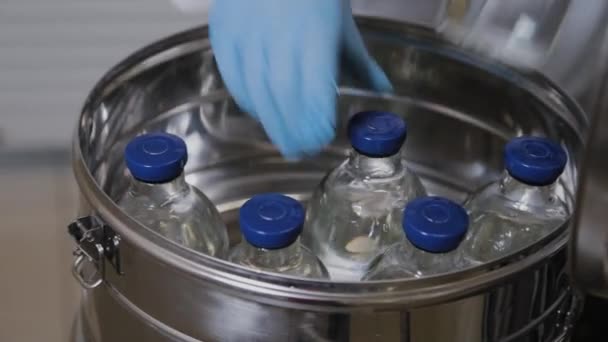 Laboratoriummedewerker stopt medicijnflesjes in sterilisatie container. — Stockvideo