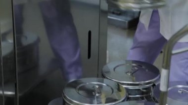 Laboratuvar çalışanı tıbbi malzemeleri sterilize etmek için otomatik klavsen kullanılabilir metal kapları yüklüyor..