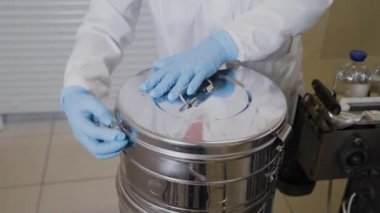 Laboratuvar çalışanı ilaç şişelerini sterilizasyon kabına koyuyor..