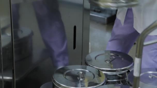 Funcionário do laboratório carrega recipientes de metal autoclaváveis para esterilizar suprimentos médicos . — Vídeo de Stock