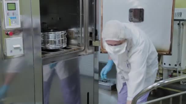 Працівник лабораторії завантажує автоклавні металеві контейнери для стерилізації медичних виробів . — стокове відео