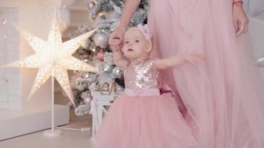 Güzel bir anne, bir yaşında güzel elbiseli bir kız çocuğu ve yeni yıl dekoru. Yeni Yıl 2020.