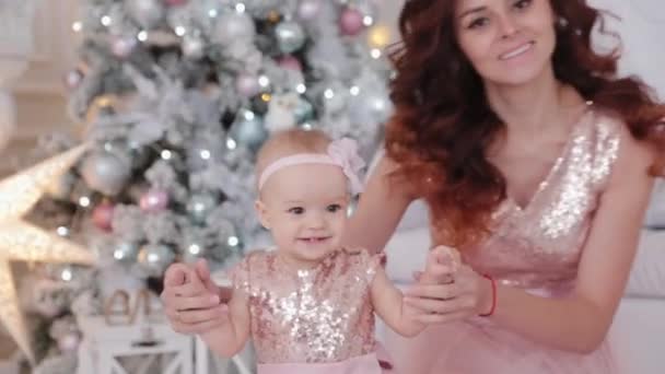 Bela mãe com uma filha de um ano de idade em belos vestidos e decoração de Ano Novo. Ano Novo 2020 . — Vídeo de Stock