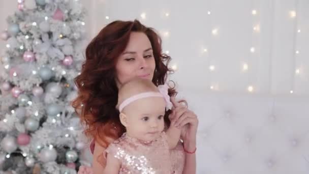 Hermosa madre con una hija de un año de edad, con hermosos vestidos y decoración de Año Nuevo. Año Nuevo 2020 . — Vídeo de stock