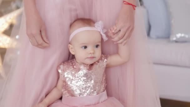 Gyönyörű anya egy egyéves kislánnyal, gyönyörű ruhákban és szilveszteri dekorációban. Új év 2020. — Stock videók