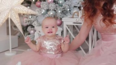 Güzel bir anne, bir yaşında güzel elbiseli bir kız çocuğu ve yeni yıl dekoru. Yeni Yıl 2020.