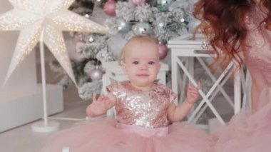 Güzel bir anne, bir yaşında güzel elbiseli bir kız çocuğu ve yeni yıl dekoru. Yeni Yıl 2020.