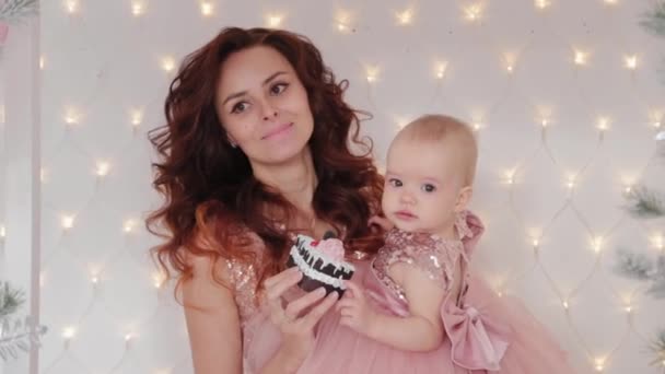 Schöne Mutter mit einer einjährigen Tochter in schönen Kleidern und Silvesterdekor. Neues Jahr 2020. — Stockvideo
