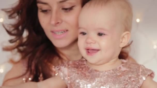 Krásná matka s jednoletou dcerou v krásných šatech a novoroční výzdobě. Nový rok 2020. — Stock video