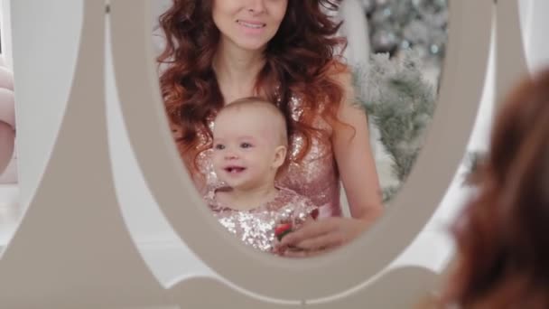 Bela mãe com uma filha de um ano de idade em belos vestidos e decoração de Ano Novo. Ano Novo 2020 . — Vídeo de Stock
