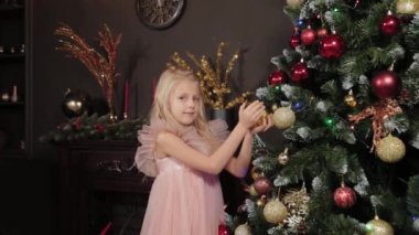 Yeni yıl ağacının yanında 10 yaşında bir kız elinde yeni yıl oyuncağı tutuyor. Yeni Yıl 2020.