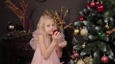 Yeni yıl ağacının yanında 10 yaşında bir kız elinde yeni yıl oyuncağı tutuyor. Yeni Yıl 2020.