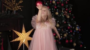 Yeni yıl ağacının yanında 10 yaşında bir kız elinde yeni yıl oyuncağı tutuyor. Yeni Yıl 2020.