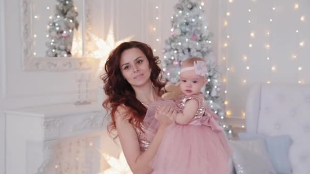 Όμορφη μητέρα με μια κόρη ενός έτους με όμορφα φορέματα και διακόσμηση Πρωτοχρονιάς. Νέο έτος 2020. — Αρχείο Βίντεο