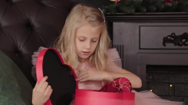 Ein zehnjähriges glückliches Mädchen öffnet ein Neujahrsgeschenk. frohes neues Jahr 2020. — Stockvideo