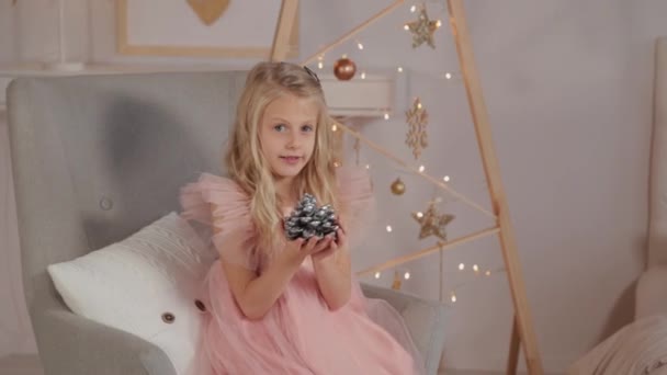 Une jeune fille de neuf ans dans le décor du Nouvel An tient un jouet du Nouvel An dans ses mains. Nouvel An 2020 . — Video