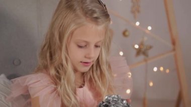 Yeni yıl dekorunda 9 yaşında bir kız elinde bir yeni yıl oyuncağı tutuyor. Yeni Yıl 2020.