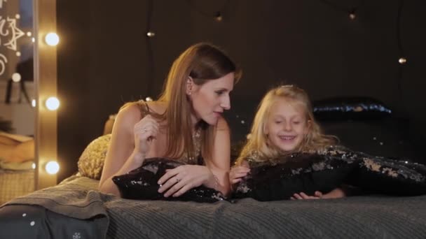 Schöne und glückliche Mutter mit Tochter am Neujahrsbaum auf dem Bett. frohes neues Jahr 2020. — Stockvideo