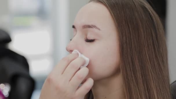 Professionell makeup artist torkar en klient med en bomullspad doppad i en speciell gel. — Stockvideo
