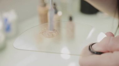 Profesyonel makyöz kadın palette makyaj kremi karıştırıyor..