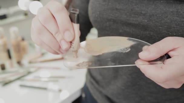 Profesional de maquillaje artista mujer agita crema de maquillaje en una paleta . — Vídeos de Stock