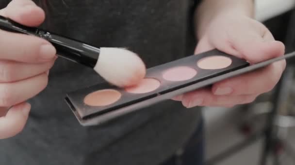 Professionele make-up artiest. Vrouw brengt stichtingspoeder op een borstel. — Stockvideo