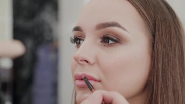 Artista de maquillaje profesional mujer pinta los labios al cliente del salón de belleza . — Vídeo de stock