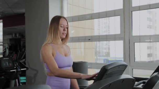 Mujer atlética con una hermosa figura se entrena en una cinta de correr . — Vídeo de stock