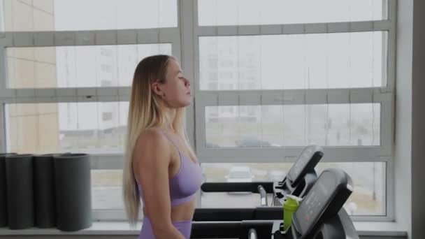 Atletische vrouw met een mooi figuur traint op een loopband. — Stockvideo