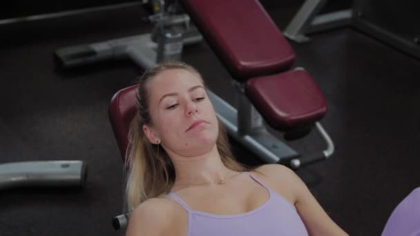 Mulher atlética com uma bela figura treina pernas no simulador no ginásio . — Vídeo de Stock