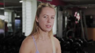 Güzel vücutlu atletik bir kadın. Kız spor salonundaki bisepsleri simülatörde çalıştırıyor..