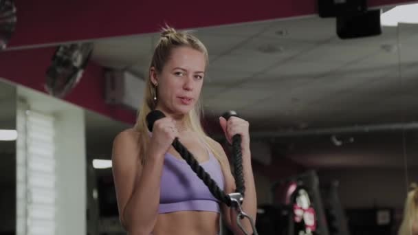 Mujer atlética con una hermosa figura. Chica entrena bíceps en el simulador en el gimnasio . — Vídeo de stock