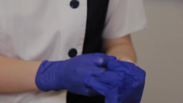 Professionelle Kosmetikerin zieht blaue Gummihandschuhe an. — Stockvideo