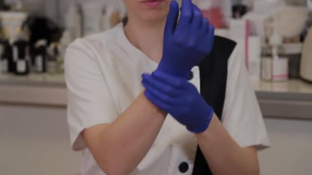 Esthéticienne professionnelle met des gants en caoutchouc bleu . — Video