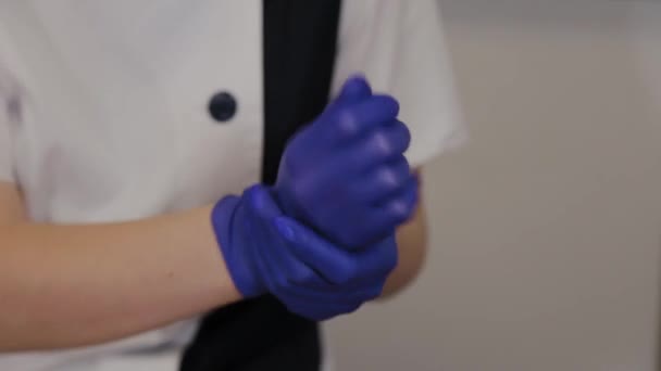 Professionelle Kosmetikerin behandelt blaue Gummihandschuhe mit einem Antiseptikum. — Stockvideo